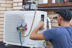 the worker installs the outdoor unit of the air conditioner on the wall of the house